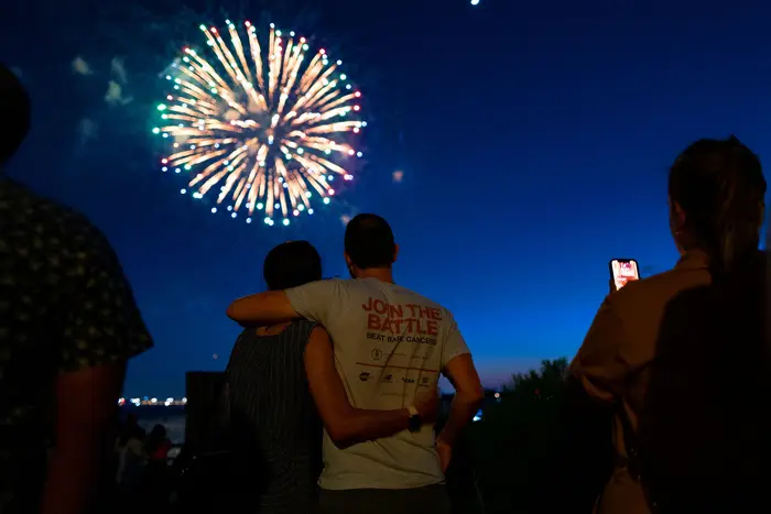 New Yorkers look at the fireworks in the New York Harbor, next to the NYC skyline